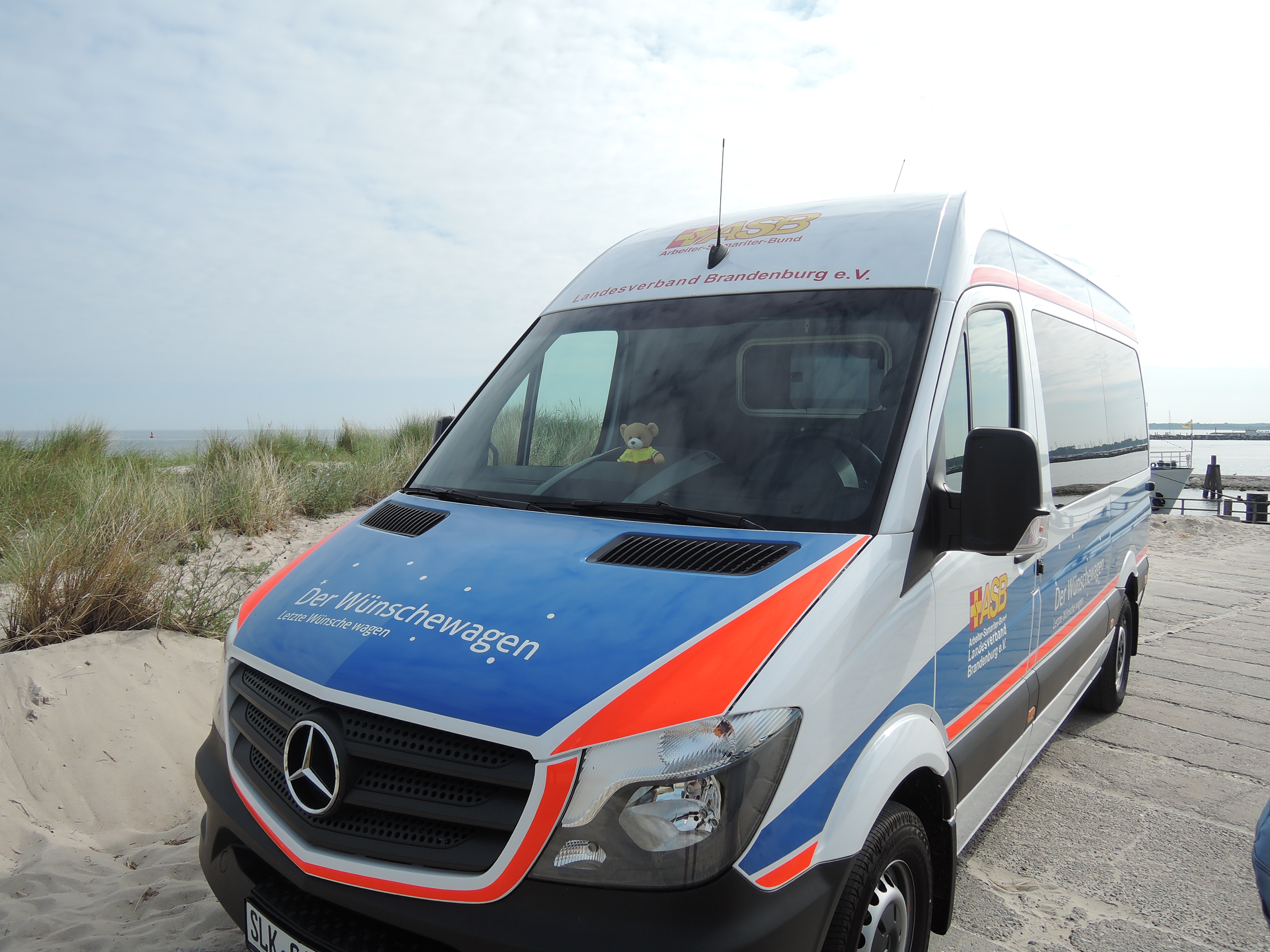 Der Wünschewagen steht vor den Dünen an der Ostsee. 