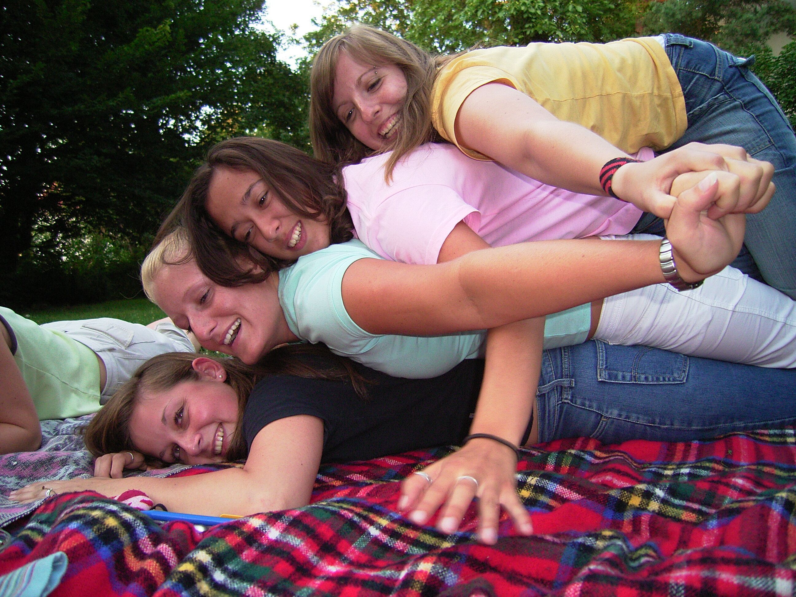 4 Jugendliche liegen lachend auf einer Wiese übereinandergestalpelt