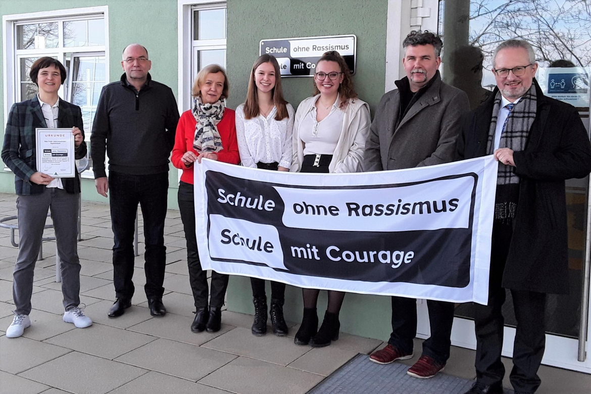 ASB22_FJG_Verleihung-24.2.22_c_FJG_1.png Eine Gruppe von Menschen hält eine Fahne hoch