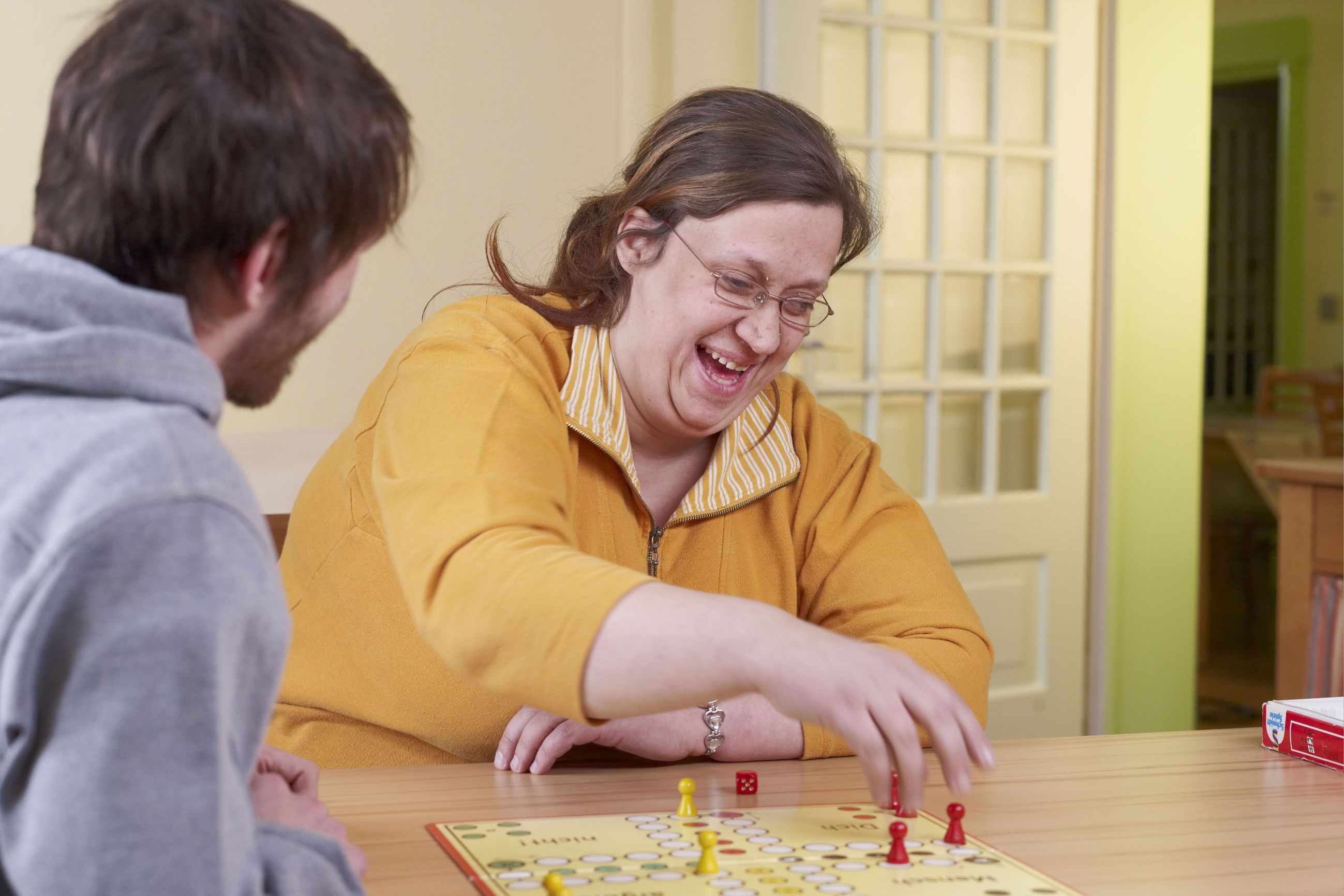 Eine Frau spielt ein Brettspiel mit einem junge  Mann.